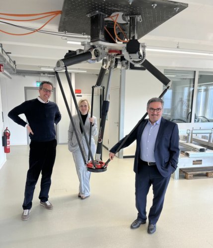 Zwei Männer und eine Frau neben einem Roboter